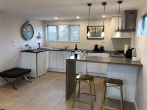 a kitchen with a counter and two bar stools at Self contained studio apartment close to Mission Estate in Napier