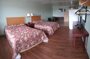 a hotel room with two beds and a wooden floor at Chimo Motel in Cochrane