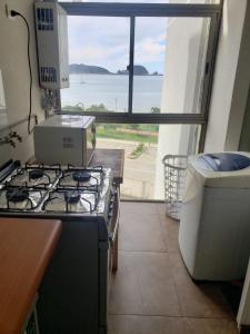 a kitchen with a stove and a view of the ocean at Dichato Borde Bahía Azul in Tomé