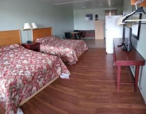 Habitación de hotel con 2 camas y escritorio en Chimo Motel, en Cochrane