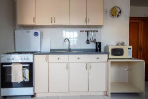 a kitchen with white cabinets and a sink and a microwave at Aruba Sunrise Studio Near Baby Beach, San Nicolas in San Nicolas