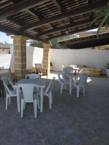 a patio with white tables and chairs under a roof at Casa Rustikò in Marsala