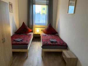 two beds in a small room with a window at Neue Ferien Monteurwohnung mit 3 Schlafzimmer 22 in Wefensleben