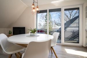 a white dining room with a white table and white chairs at Strandhaus 3 OG in Marienfelde