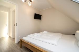 a white bed in a room with a tv on the wall at Strandhaus 3 OG in Marienfelde