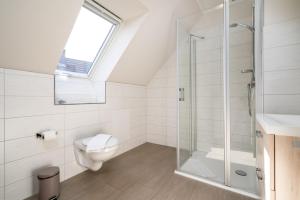 a bathroom with a toilet and a glass shower at Strandhaus 3 OG in Marienfelde +24 photos