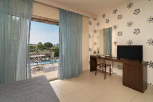 a bedroom with a desk with a television and a balcony at Tsokas Hotel in Finikounta