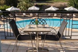a table and chairs next to a swimming pool at Tsokas Hotel in Finikounta