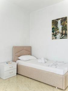a bedroom with a bed and a painting on the wall at Cozy Village Guesthouse in Delvinë
