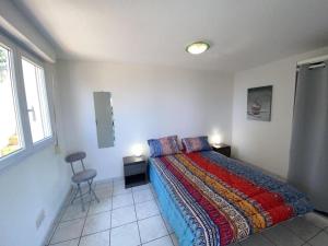 Un dormitorio con una cama, una silla y una ventana en L'appartement des Albères, en Laroque-des-Albères
