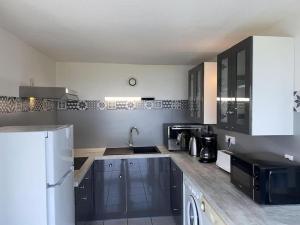 Una cocina con un refrigerador blanco y un fregadero. en L'appartement des Albères, en Laroque-des-Albères 4 fotos más