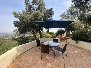 Un patio con una mesa y sillas y una sombrilla. en L'appartement des Albères, en Laroque-des-Albères