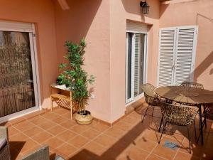 een patio met een tafel en stoelen en een plant bij La Isla Casa de Franco - Condado De Alhama Golf Course in Alhama de Murcia