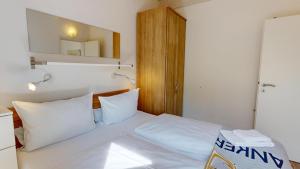 a bedroom with a bed with white sheets and a mirror at Feriendorf Südstrand Haus 23 in Pelzerhaken