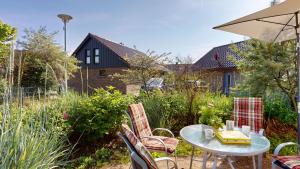 a table with chairs and an umbrella in a garden at Feriendorf Südstrand Haus 23 in Pelzerhaken