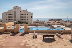 una piscina di fronte ad alcuni edifici e all'oceano di Bungalow Barlovento Playa ad Arenales del Sol Altre 20 foto
