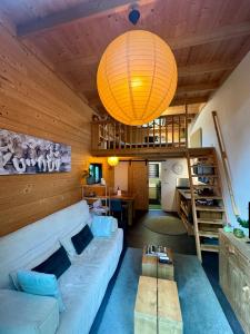 uma sala de estar com um sofá e um lustre em Tiny House met Hottub op de Veluwe em Beekbergen