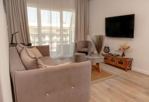 uma sala de estar com um sofá e uma televisão de ecrã plano em Porta Mare Dziwnów Zacisze Resort & Spa em Dziwnów