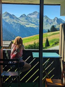 a young girl sitting on a balcony looking out at the mountains at Combe Blanche 1217 in Manigod