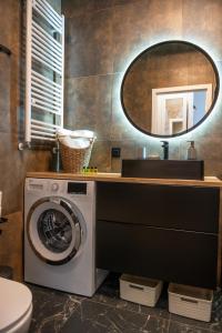 uma casa de banho com uma máquina de lavar roupa e um espelho. em Porta Mare Dziwnów Zacisze Resort & Spa em Dziwnów