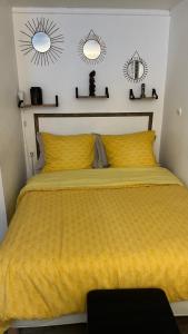 ein Schlafzimmer mit einem gelben Bett mit zwei Spiegeln an der Wand in der Unterkunft Adorable studio 20m2 in Aubervilliers