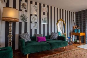 a living room with a green couch and striped wall at SuperAttico Bella Bellù in Palermo