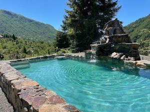 a swimming pool with a rock wall and blue water at ხის სახლი in Keda