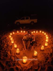 two men sitting in a circle of candles in the sand at Lukasa camp Wadi Rum in Wadi Rum