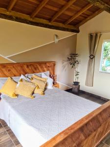um quarto com uma cama de madeira e almofadas amarelas em PENEDO ACONCHEGO LOFT: VISTA, CONFORTO E NATUREZA! em Penedo