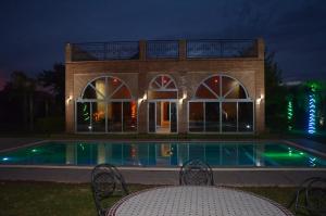 a building with a swimming pool at night at VillaAbrajeimmo in Marrakech