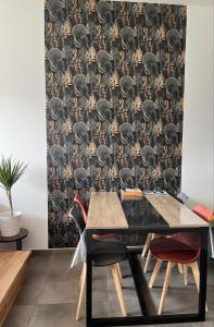 a dining room with a black table with red chairs and a wallpaper at maison cosy centre-ville avec jardin, clim in Lens +15 photos