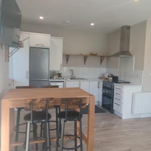 a kitchen with a wooden table and bar stools at Buvinda Self Catering in Tullyallen