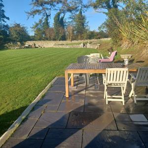 a wooden table and chairs on a patio with a lawn at Buvinda Self Catering in Tullyallen +5 photos