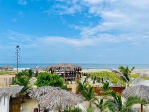 een strand met een aantal rieten parasols en de oceaan bij Un Dia Boutique Resort in Playas