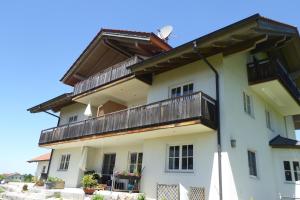 a large white building with a wooden balcony at Ferienwohnungen Florian Pletzenauer in Gstadt am Chiemsee