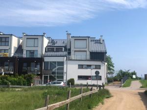 a white building with a fence next to a dirt road at Apartament Nowy Świat Puck in Puck