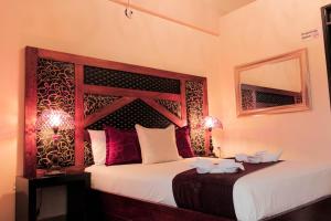 a bedroom with a bed with a wooden headboard and a mirror at Hotel Plaza Garibaldi in Caldas