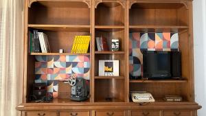 a wooden book shelf with a tv and a desk at Casa di Nonna Tina in Pisa