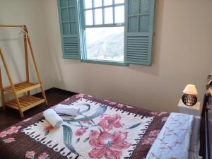 a bedroom with a bed with a window and a rug at Casinha da Lela in Ouro Preto
