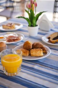 a table topped with plates of pastries and orange juice at Tsokas Hotel in Finikounta