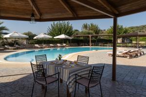 a table with chairs next to a swimming pool at Tsokas Hotel in Finikounta