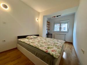 a small bedroom with a bed in a room with a window at Specialty Coffee Apartment in Skopje +4 photos