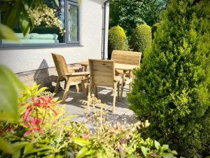 un patio con 2 sillas y una mesa en un jardín en 3-bedroom bungalow, central Ambleside with parking, en Ambleside