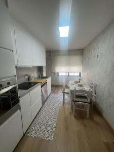 a kitchen with white cabinets and a table in it at Puerto de Bueu, Centro in Bueu