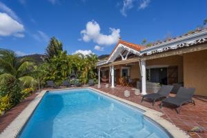 a swimming pool in front of a house at Villa Cap Sud avec piscine et vue mer in Les Anses-dʼArlets