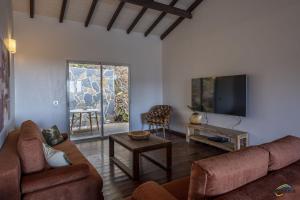 a living room with a couch and a flat screen tv at Villa Cap Sud avec piscine et vue mer in Les Anses-dʼArlets
