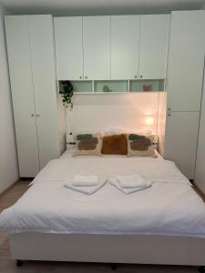 a bed with white cabinets and two towels on it at Siebenbürger Haus in Sibiu