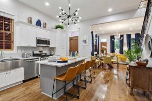 a kitchen with white cabinets and a kitchen island with chairs at Designer Home Walking Distance To The French Quarter's in New Orleans