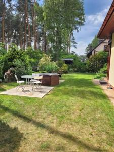 a backyard with a table and chairs in the grass at Dom wakacyjny MERLIN nad jeziorem Jodłów Sława Radzyń in Jodlow