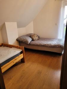 two beds in a room with wooden floors at Dom wakacyjny MERLIN nad jeziorem Jodłów Sława Radzyń in Jodlow